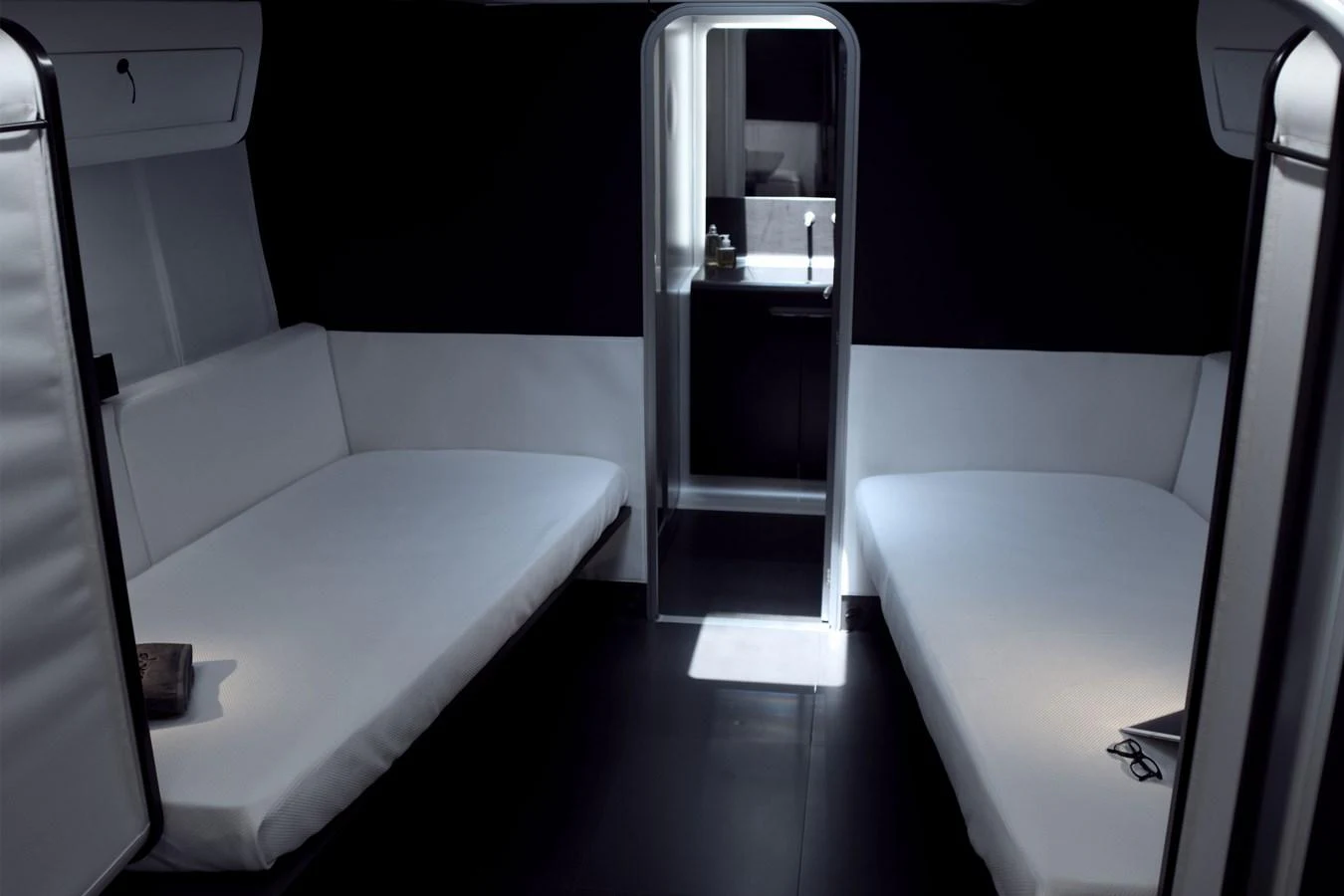 The yacht's interior features a minimalist cabin with two sleek, modern beds and a view into a compact bathroom area. aboard BULLITT Yacht for Sale