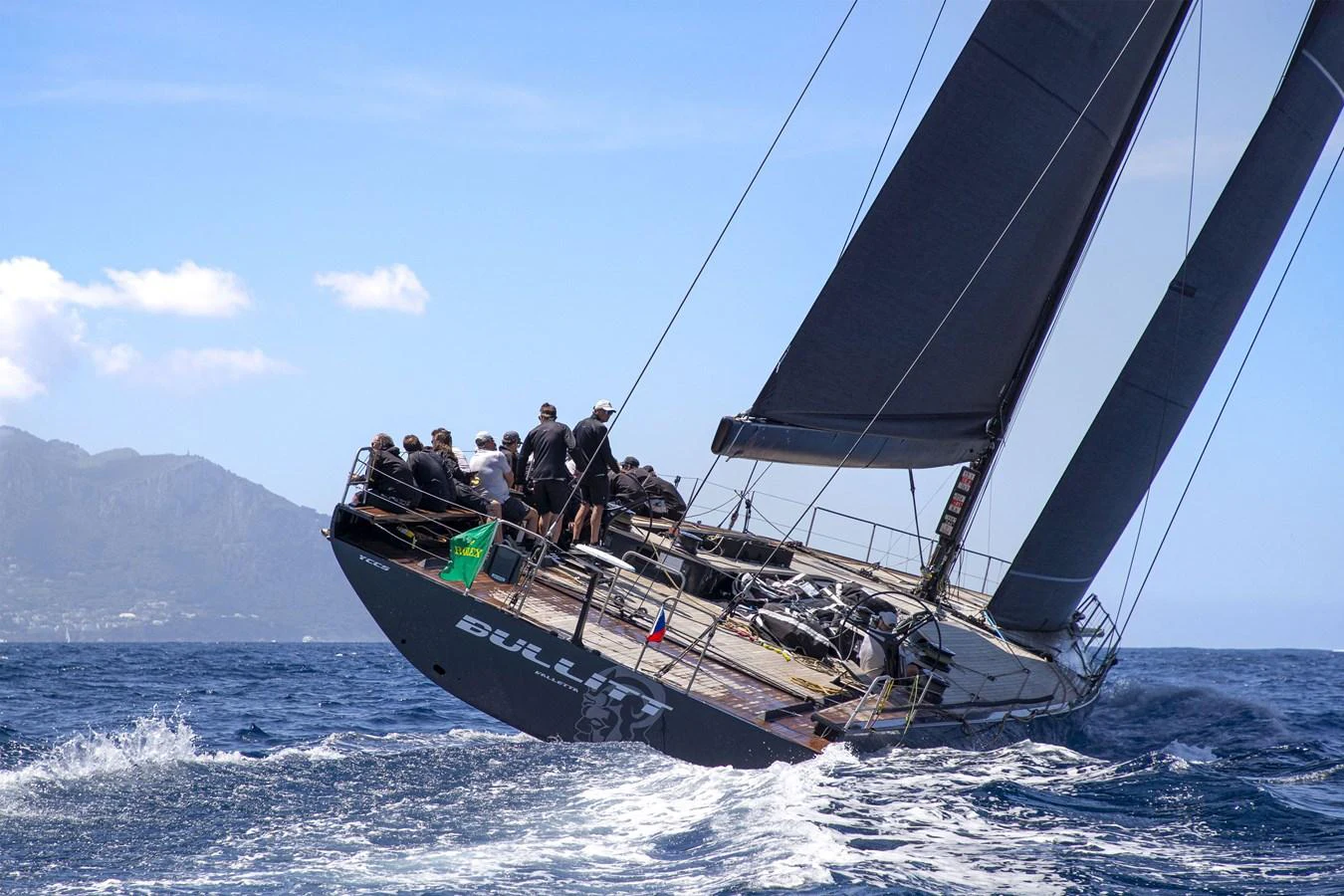 A sleek sailing yacht cuts through the waves with a crew on deck, showcasing its impressive design and performance. aboard BULLITT Yacht for Sale
