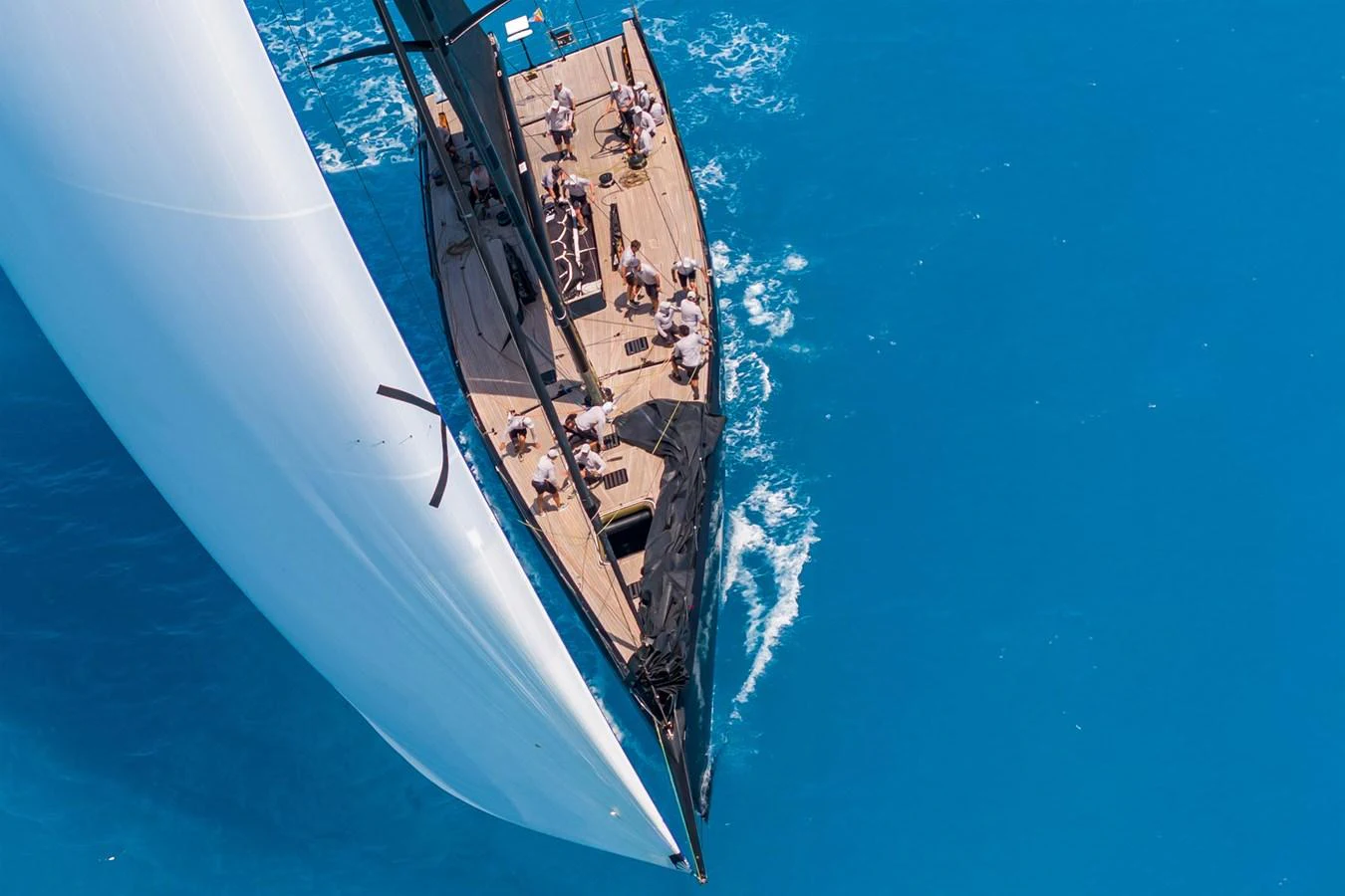 A sleek sailing yacht glides through vibrant blue waters, showcasing its elegant deck and sails. aboard BULLITT Yacht for Sale