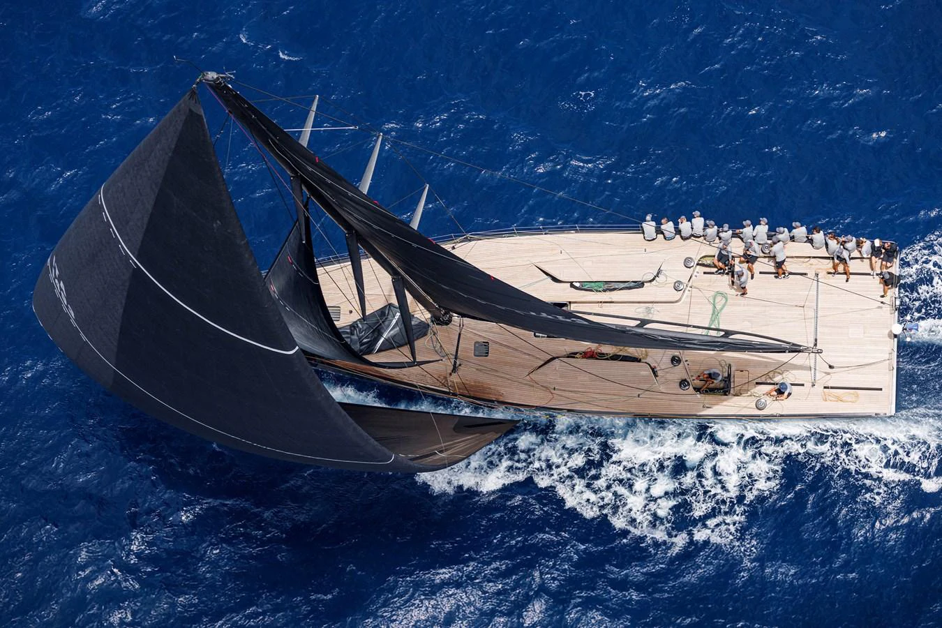 A sleek sailing yacht glides through the vibrant blue ocean with its sails fully extended. aboard BULLITT Yacht for Sale