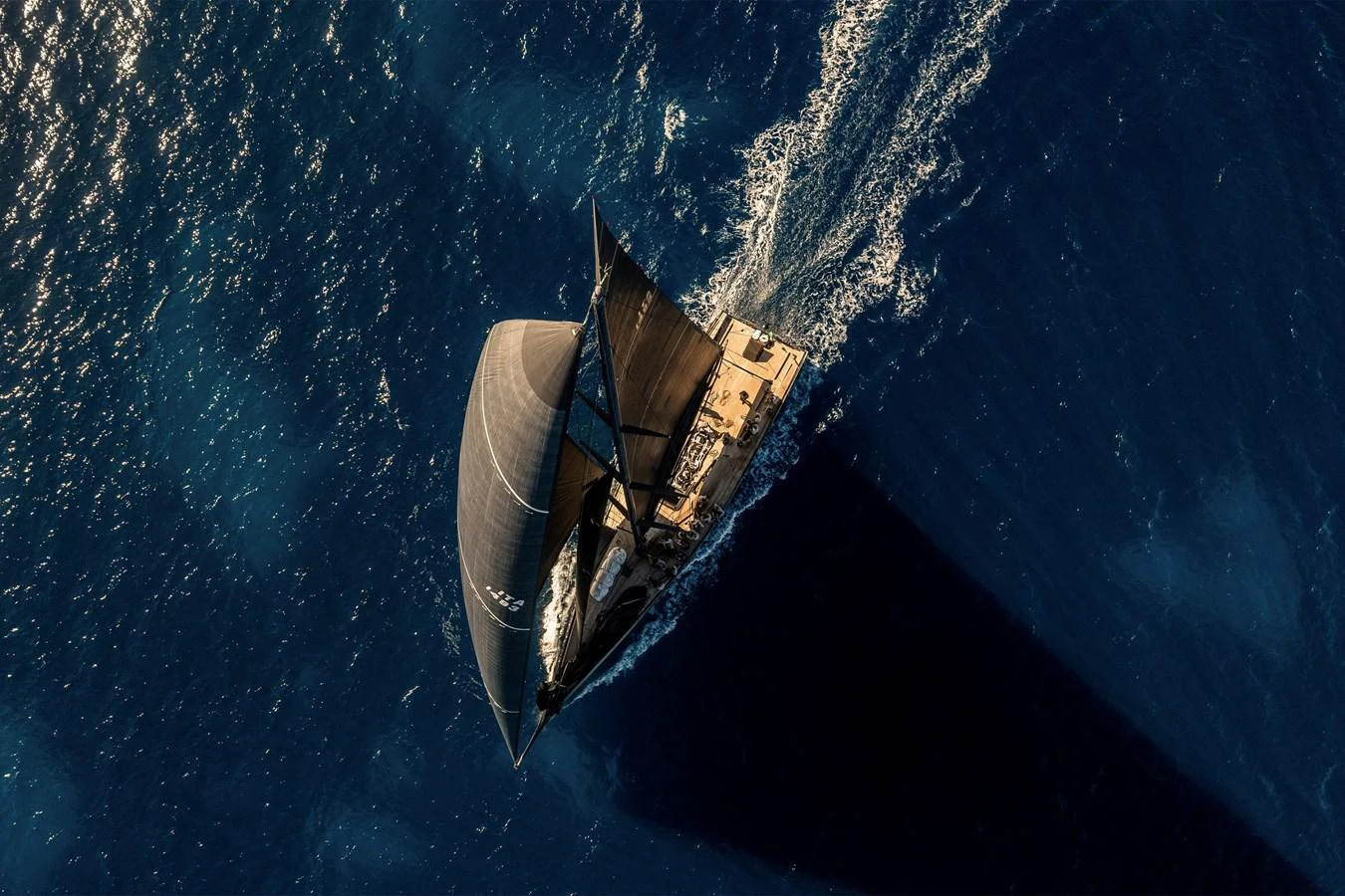 A stunning aerial view of a sleek sailing yacht cutting through the deep blue ocean waters. aboard BULLITT Yacht for Sale