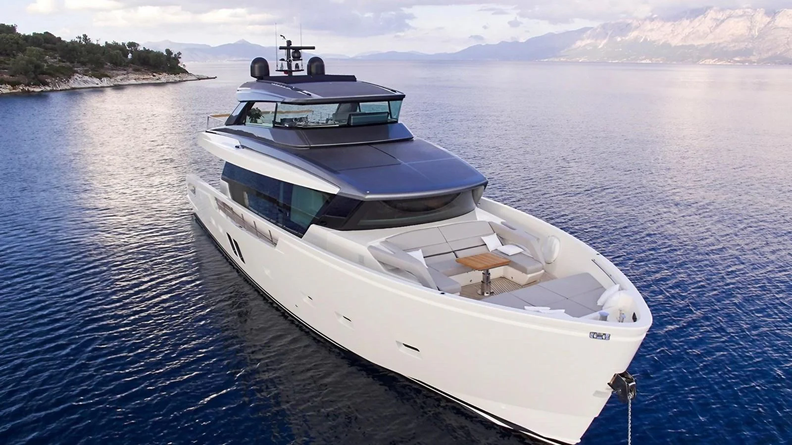 A sleek, modern yacht glides gracefully on calm waters with a stunning coastal backdrop. aboard SAHASA I Yacht for Sale