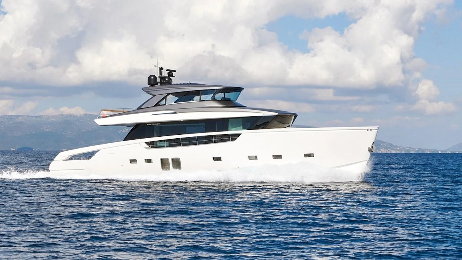 A sleek, modern yacht cruises through the open water under a partly cloudy sky. aboard SAHASA I Yacht for Sale
