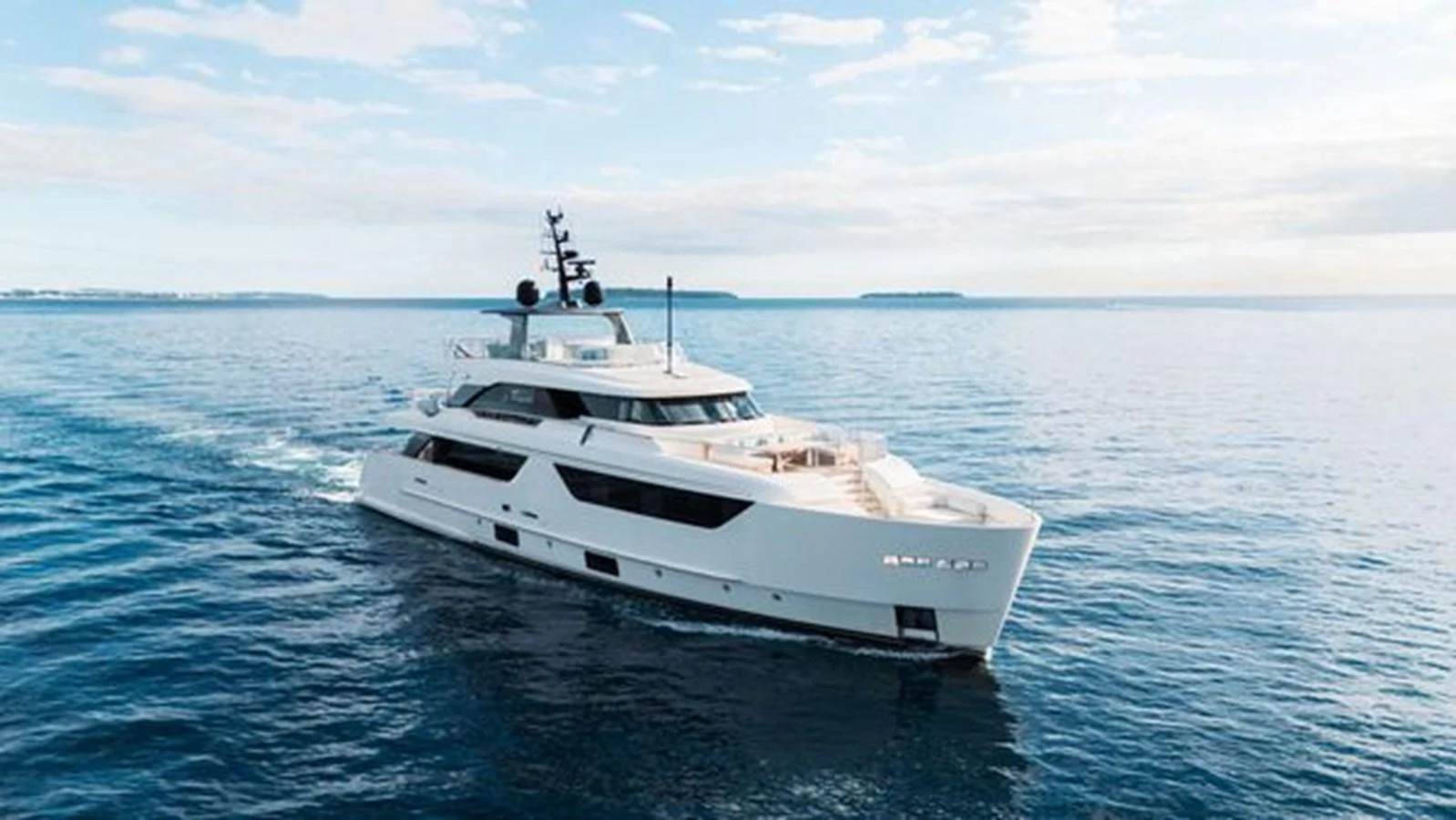 A sleek and modern yacht cruises through calm waters under a partly cloudy sky. aboard 2022 SANLORENZO SD118 Yacht for Sale
