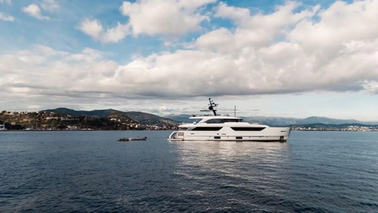 A sleek, modern yacht cruises peacefully on calm waters under a partly cloudy sky. aboard 2022 SANLORENZO SD118 Yacht for Sale