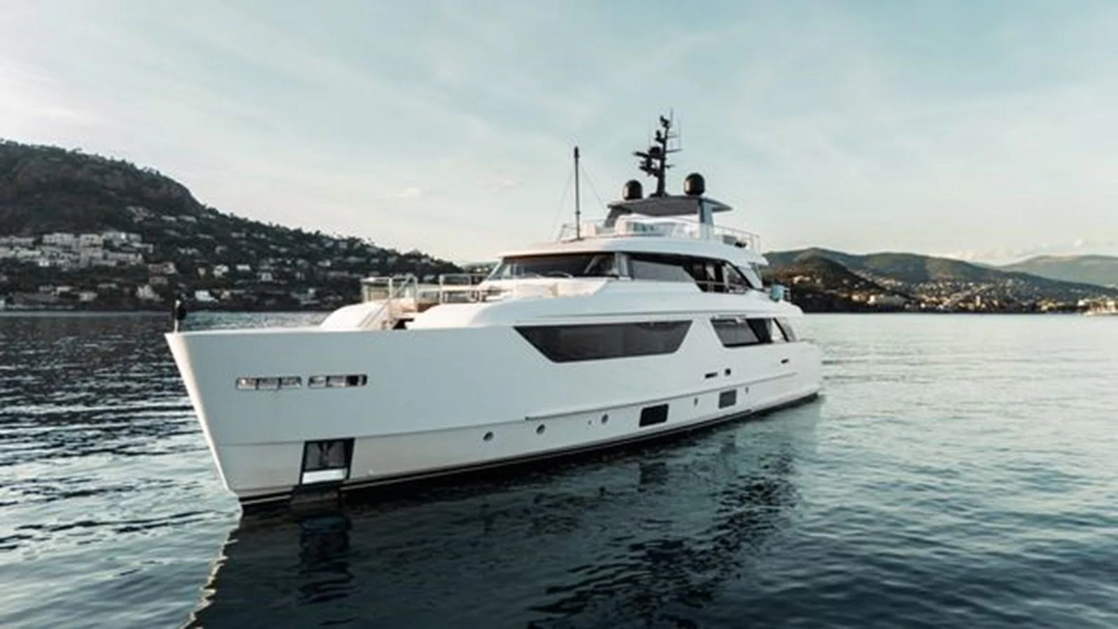 A sleek, modern yacht glides gracefully on calm waters with a scenic coastal backdrop. aboard 2022 SANLORENZO SD118 Yacht for Sale
