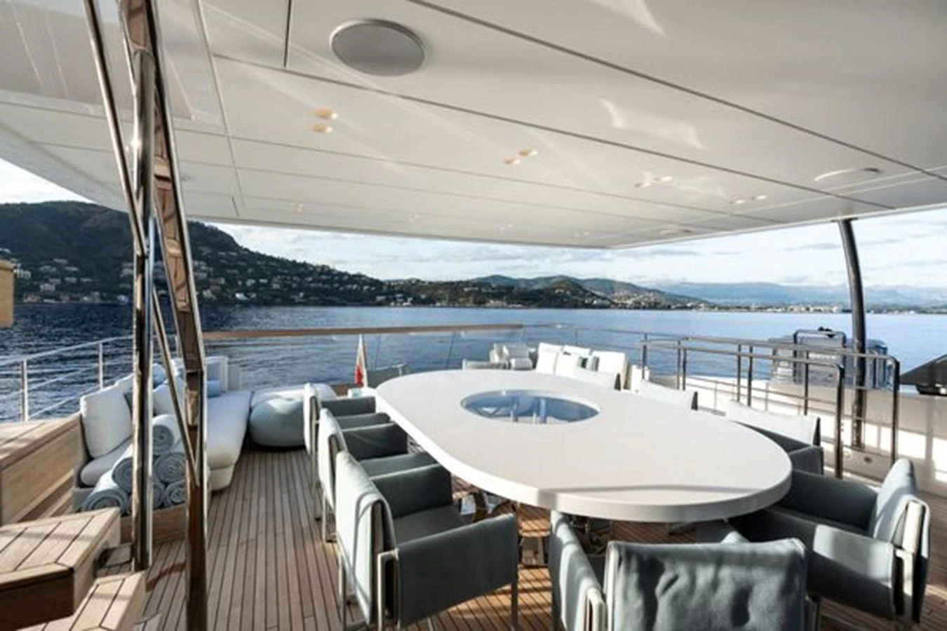 The aft deck features a spacious dining area with a large oval table and comfortable seating, offering stunning views of the surrounding waters. aboard 2022 SANLORENZO SD118 Yacht for Sale
