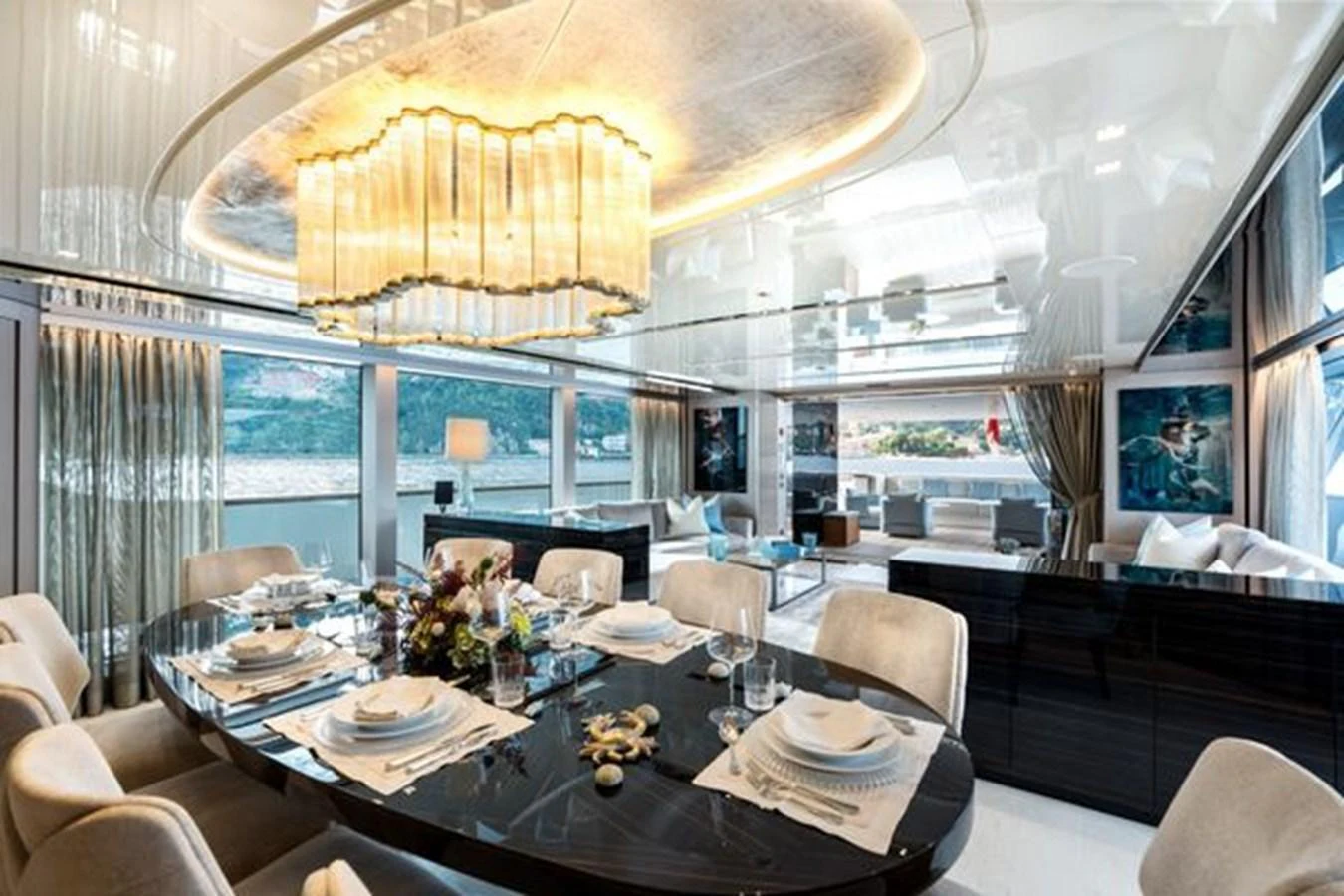 The yacht's dining area features an elegant table set for a meal, with a stunning chandelier overhead and large windows offering scenic views. aboard 2022 SANLORENZO SD118 Yacht for Sale