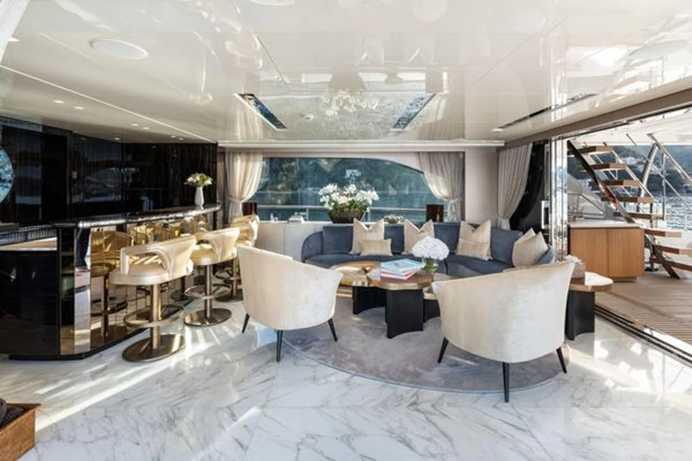The yacht's salon features luxurious seating, a bar area, and elegant decor with a view of the water. aboard 2022 SANLORENZO SD118 Yacht for Sale