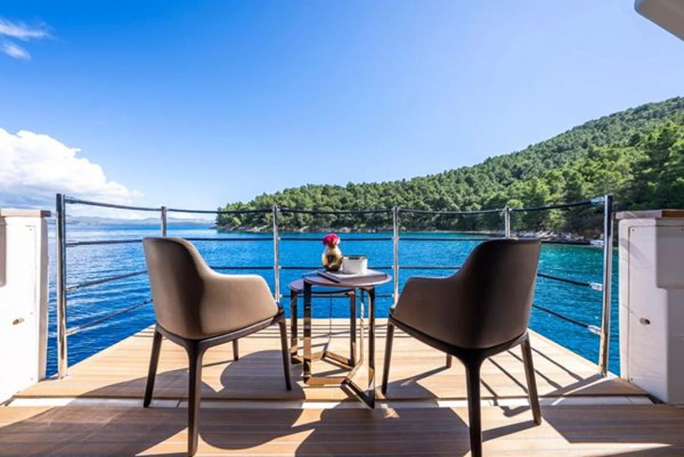 a table and chairs on a deck overlooking a body of water aboard SK Yacht for Sale