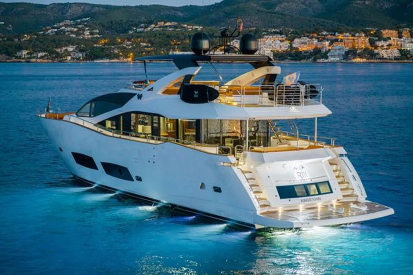 A luxurious yacht is anchored in serene waters, illuminated beautifully against a coastal backdrop. aboard 2015 SUNSEEKER 28M RIII Yacht for Sale