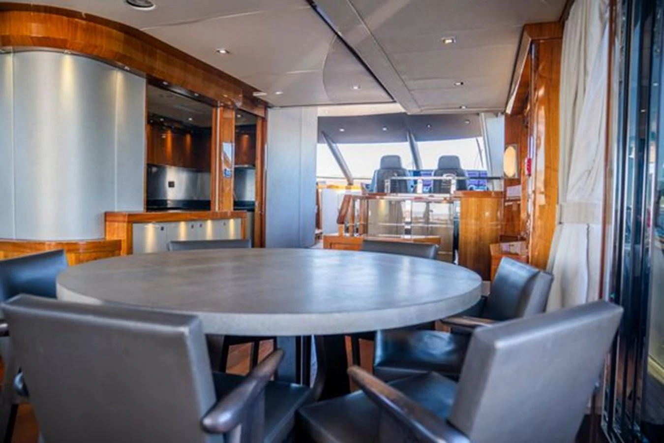 The yacht's dining area features a round table surrounded by comfortable chairs, with a view towards the helm. aboard 2015 SUNSEEKER 28M RIII Yacht for Sale