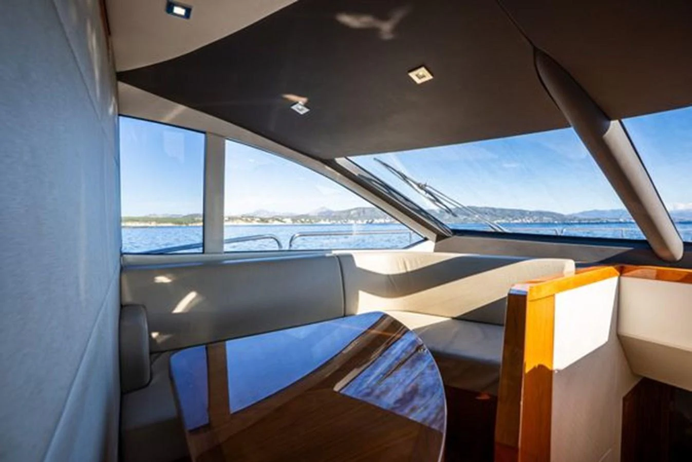 The yacht's interior features a cozy seating area with large windows offering a stunning view of the sea. aboard 2015 SUNSEEKER 28M RIII Yacht for Sale