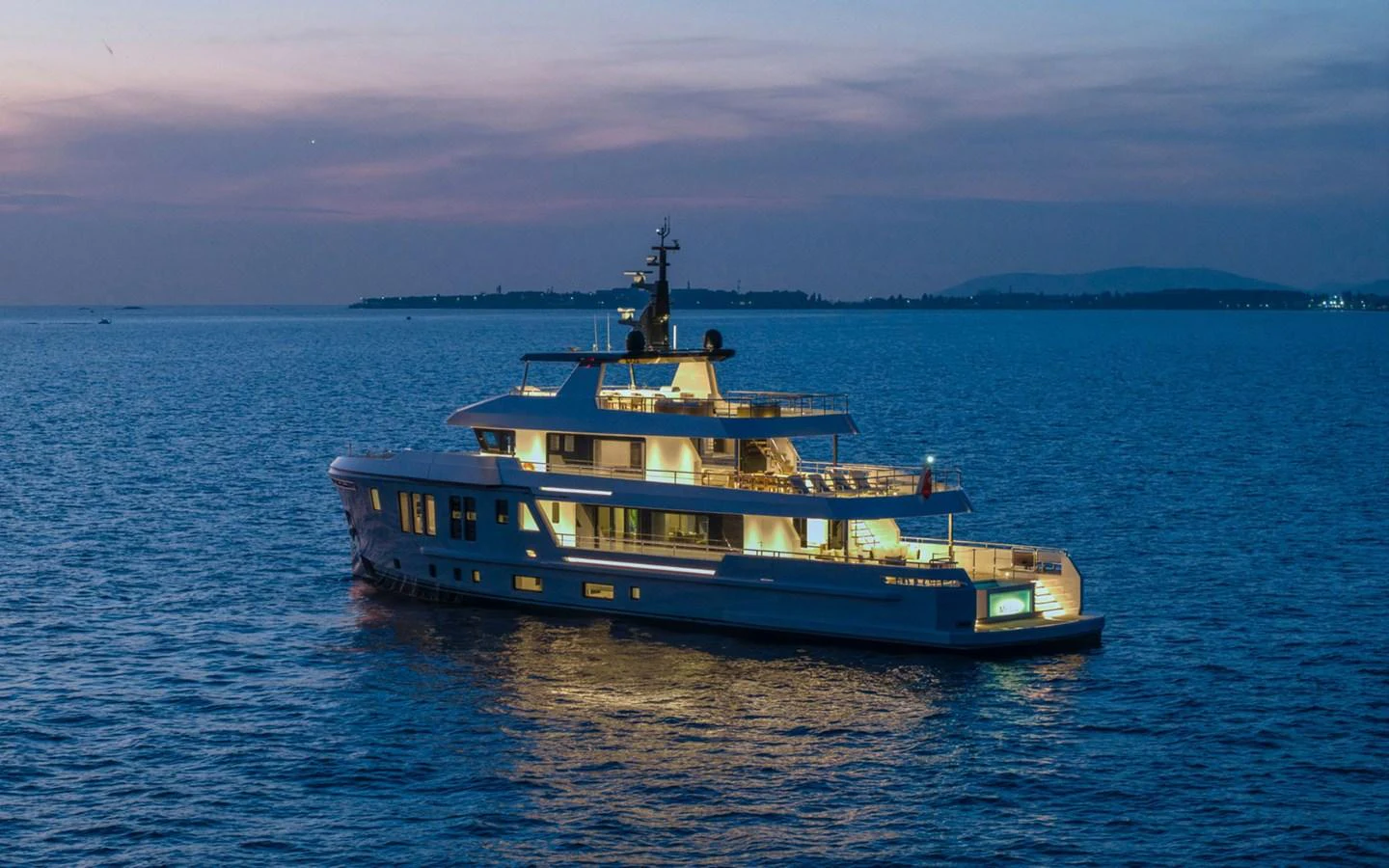 A stunning yacht is illuminated against a serene evening seascape. aboard BEE EXPLORER YACHT Yacht for Sale