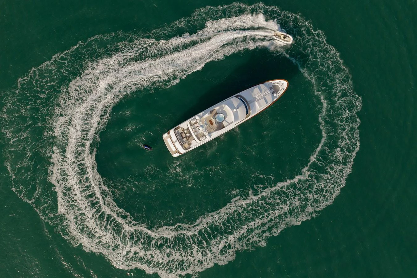 Aerial view of a yacht cruising on the water with a jet ski circling around it. aboard HOSHI Yacht for Sale