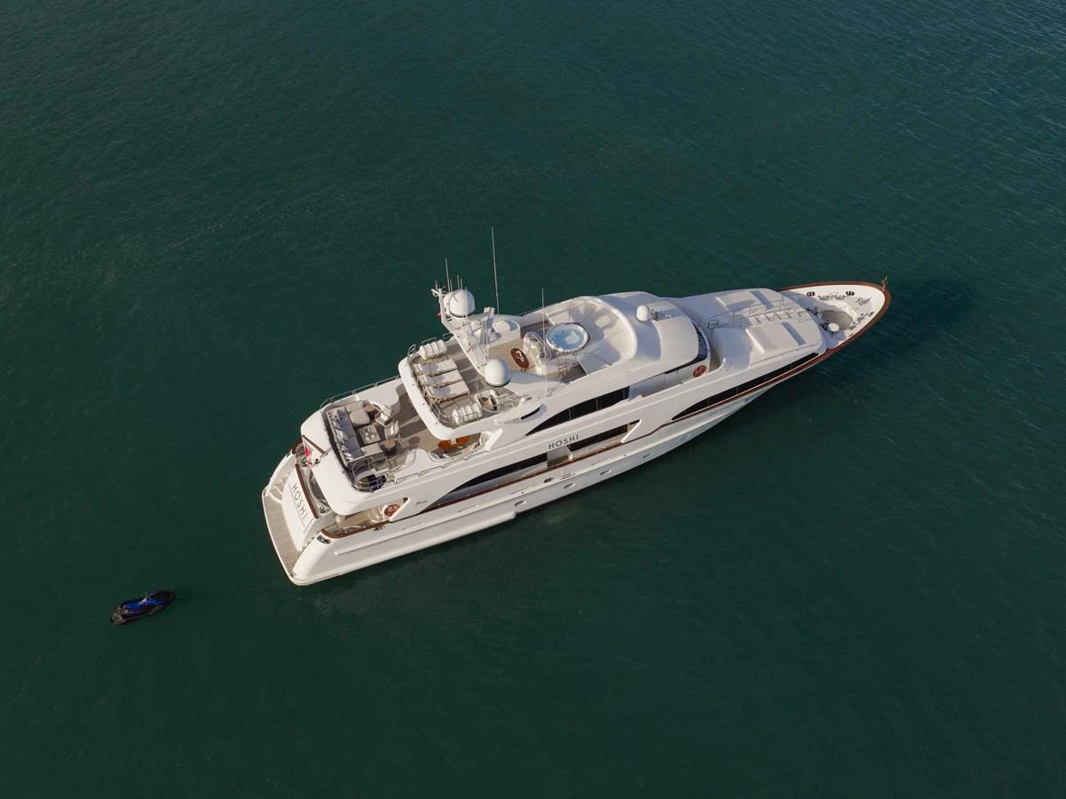 A luxurious yacht is seen from above, cruising on calm waters with a tender nearby. aboard HOSHI Yacht for Sale