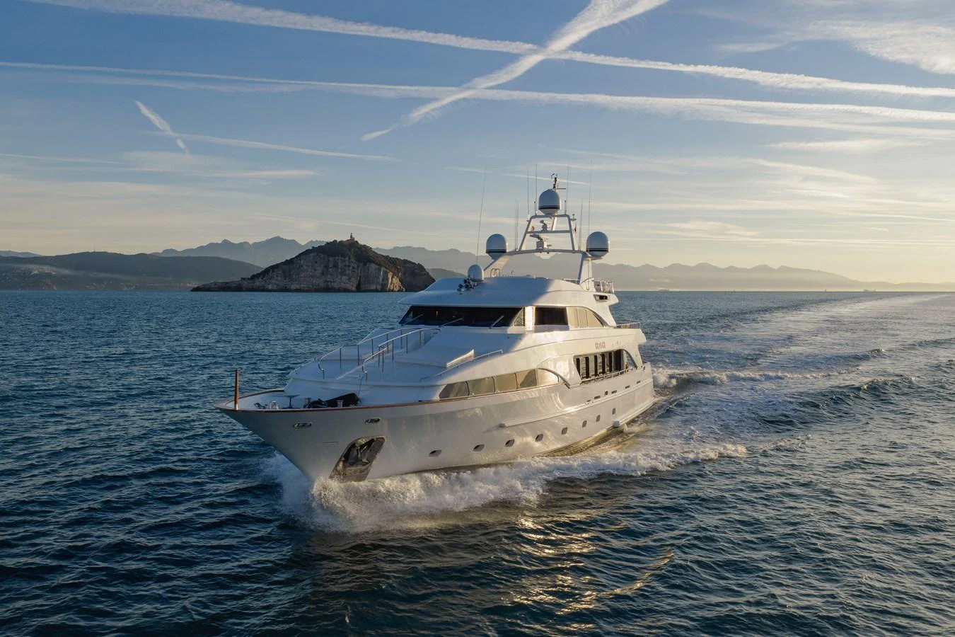 A luxurious yacht cruises gracefully on the open sea with a scenic island in the background. aboard HOSHI Yacht for Sale