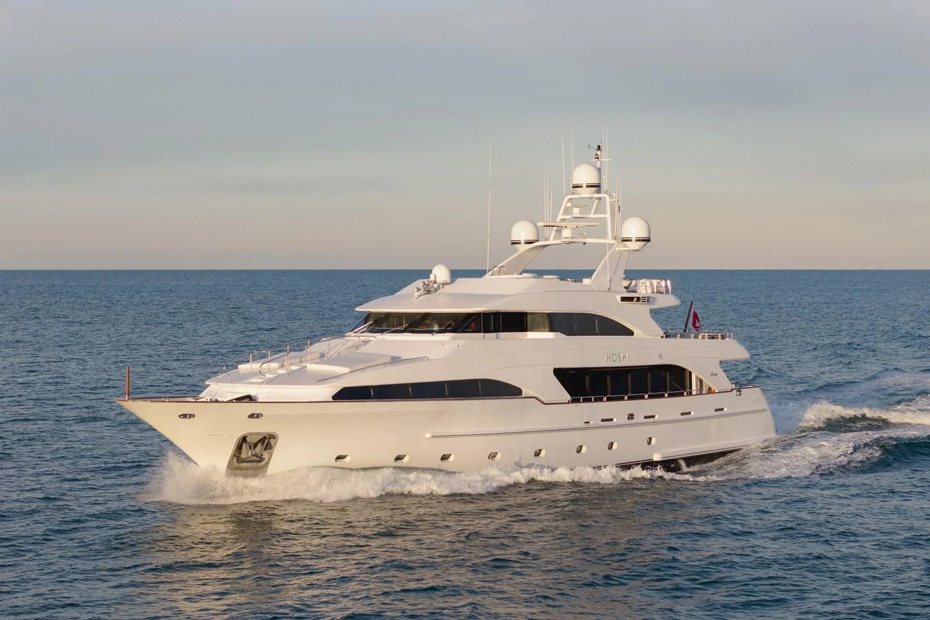 A luxurious yacht cruises through calm waters, showcasing its sleek design and elegant profile. aboard HOSHI Yacht for Sale