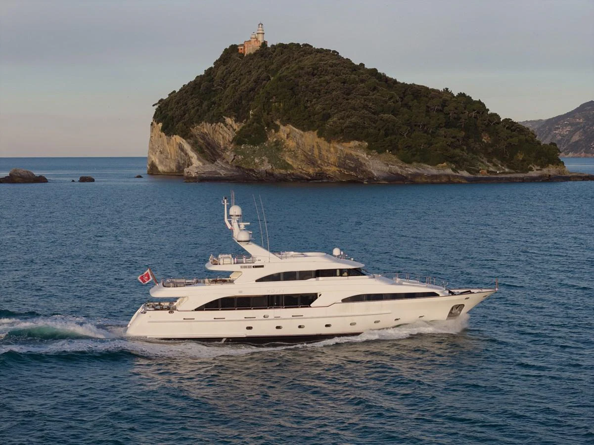 A sleek white yacht cruises past a picturesque island, showcasing its elegant design and spacious decks. aboard HOSHI Yacht for Sale