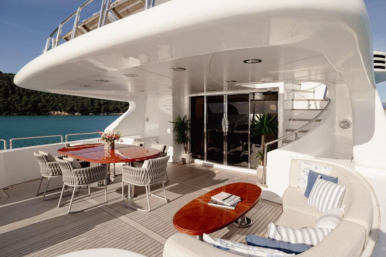 The aft deck features elegant outdoor seating and dining areas with a stunning view of the water. aboard HOSHI Yacht for Sale