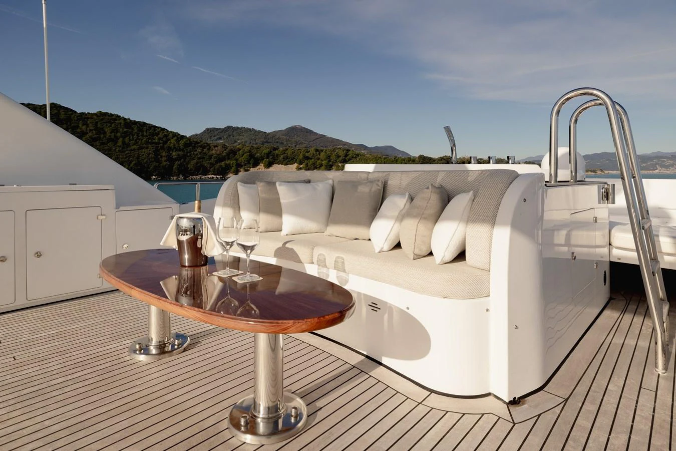The aft deck features a stylish seating area with a polished wooden table, perfect for relaxing and enjoying the view. aboard HOSHI Yacht for Sale
