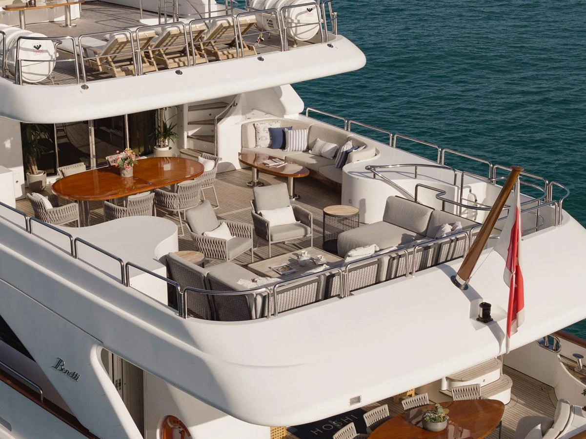 The yacht's aft deck features luxurious seating and dining areas with a stunning view of the sea. aboard HOSHI Yacht for Sale