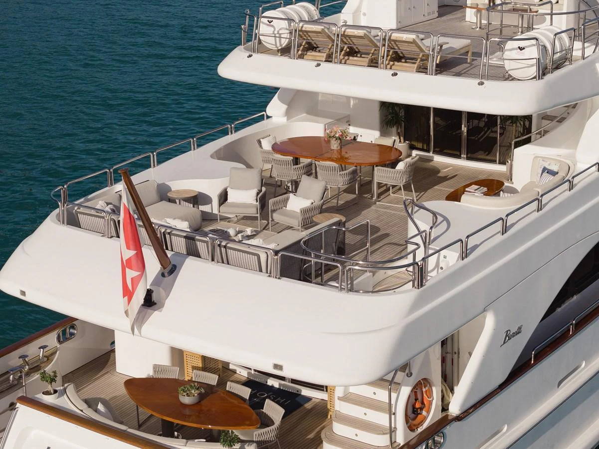 The yacht's aft deck features elegant outdoor dining and lounging areas with a view of the serene water. aboard HOSHI Yacht for Sale