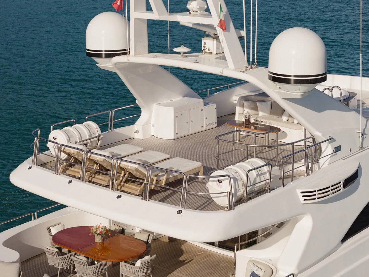 The yacht's sundeck offers luxurious lounging areas with sunbeds and a dining table, perfect for relaxation and entertainment. aboard HOSHI Yacht for Sale