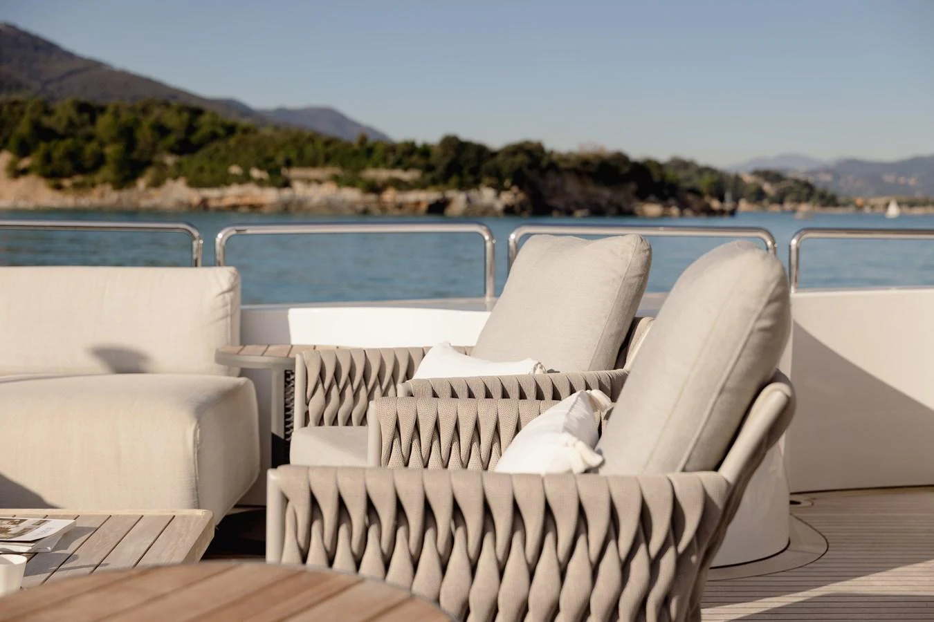 The aft deck features plush, stylish seating with a serene view of the water and distant shoreline. aboard HOSHI Yacht for Sale