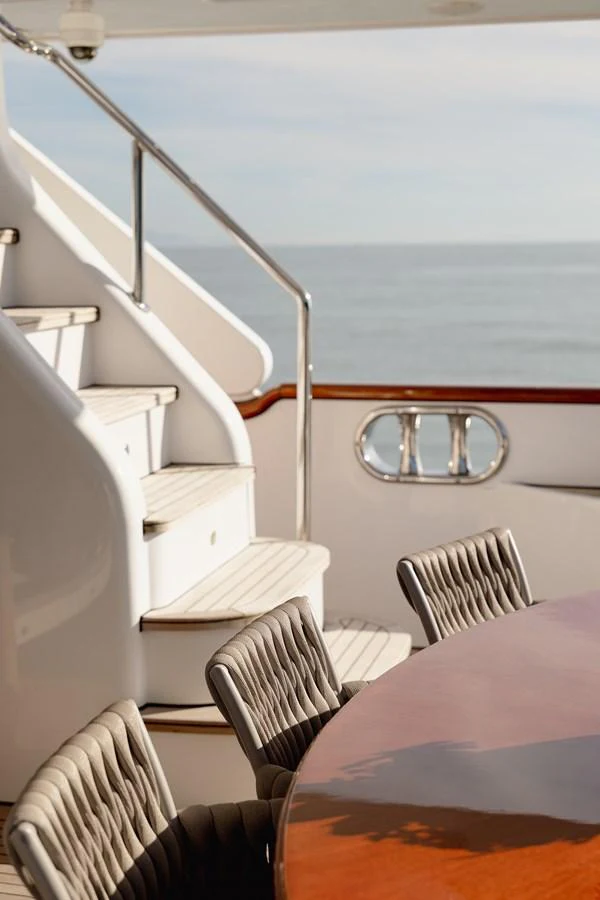 The aft deck features a polished wooden table and comfortable seating with a view of the sea. aboard HOSHI Yacht for Sale