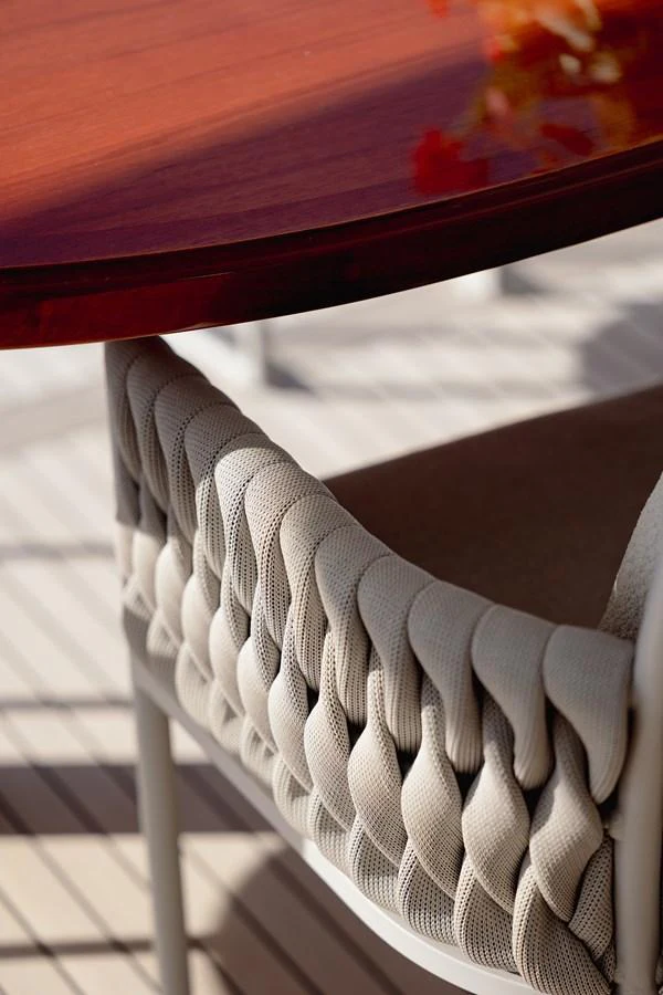 A close-up of an elegant woven chair and polished wooden table on the yacht's deck. aboard HOSHI Yacht for Sale