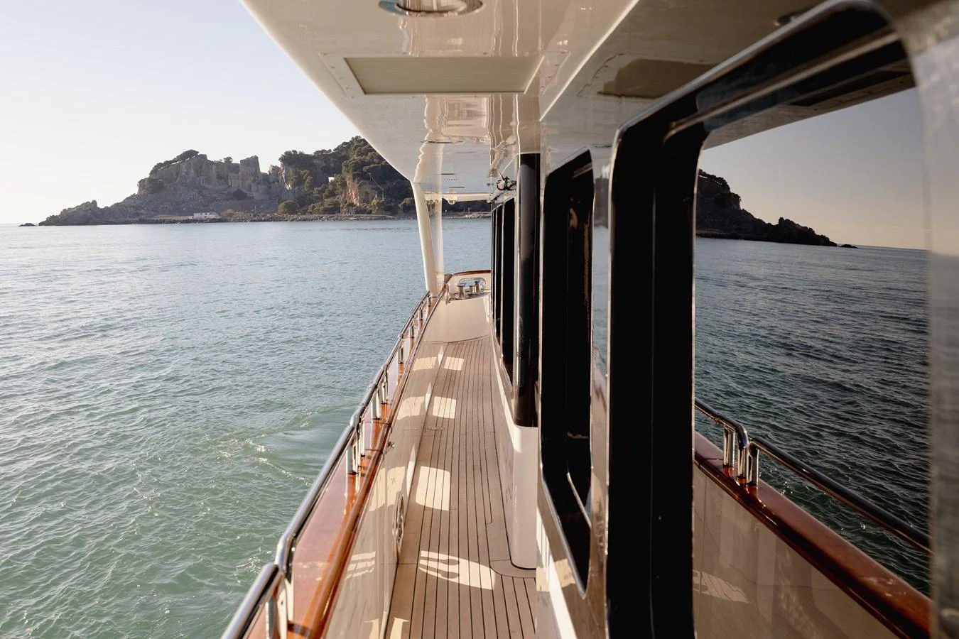 The yacht's side deck offers a serene view of the surrounding waters and distant coastline. aboard HOSHI Yacht for Sale