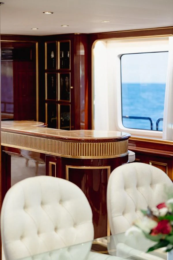 The elegant dining area features plush seating and a view of the ocean through a large window. aboard HOSHI Yacht for Sale