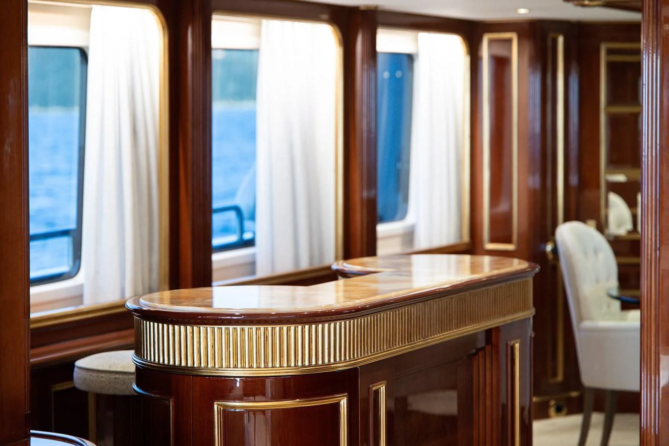 The yacht's saloon features elegant wood paneling and a polished bar area with ample natural light from large windows. aboard HOSHI Yacht for Sale