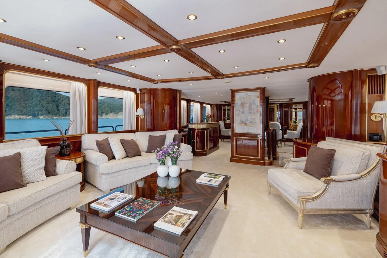 The salon features elegant furnishings with ample seating and large windows offering scenic views. aboard HOSHI Yacht for Sale