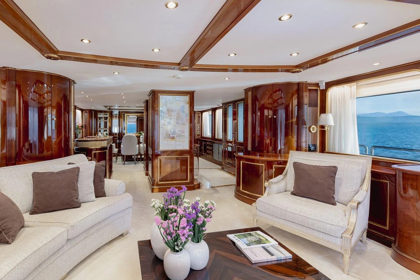 The salon features elegant furnishings with plush seating and polished wood finishes, offering a luxurious space to relax and enjoy the view. aboard HOSHI Yacht for Sale