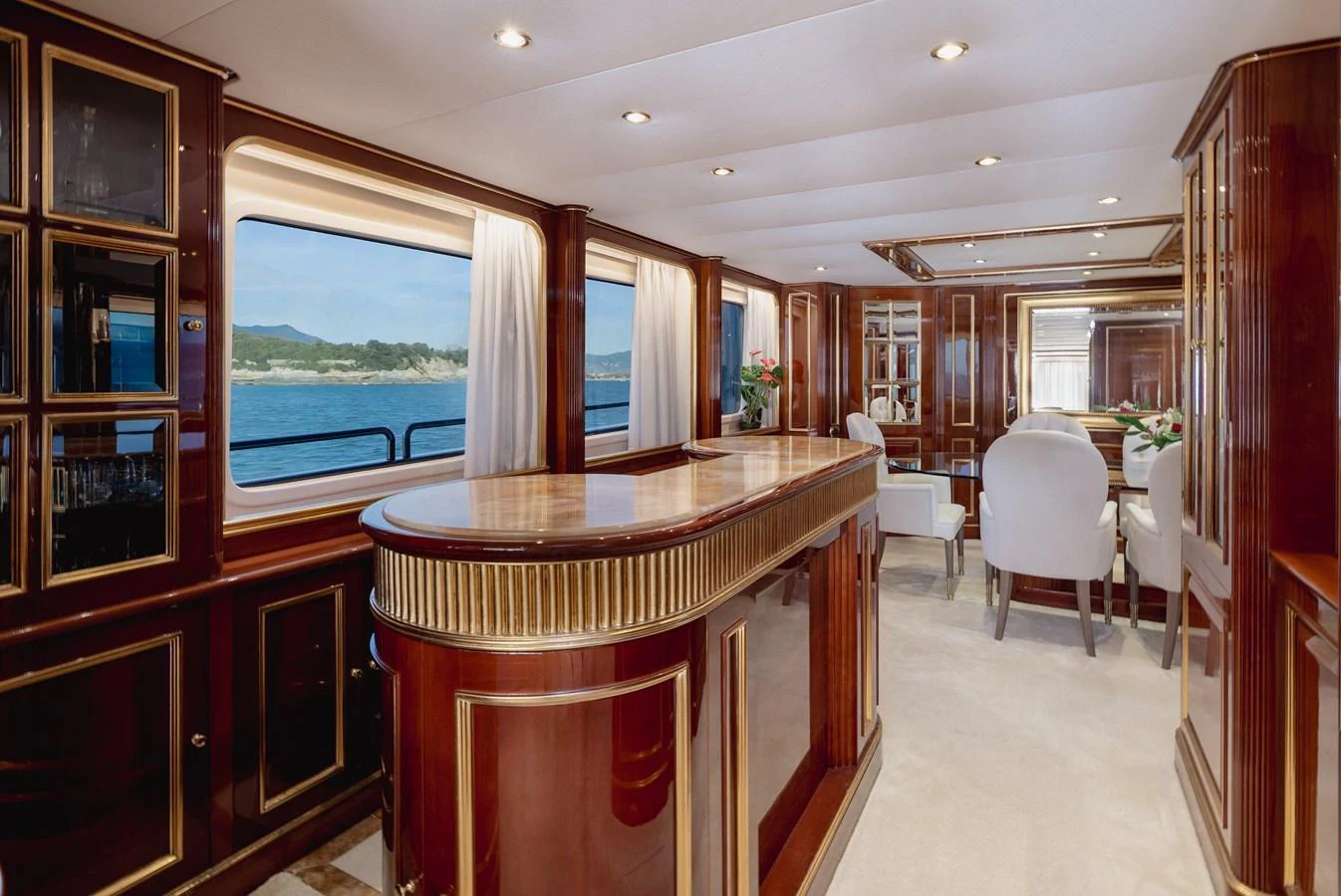 The yacht's salon features elegant wood finishes, plush seating, and large windows offering stunning views. aboard HOSHI Yacht for Sale