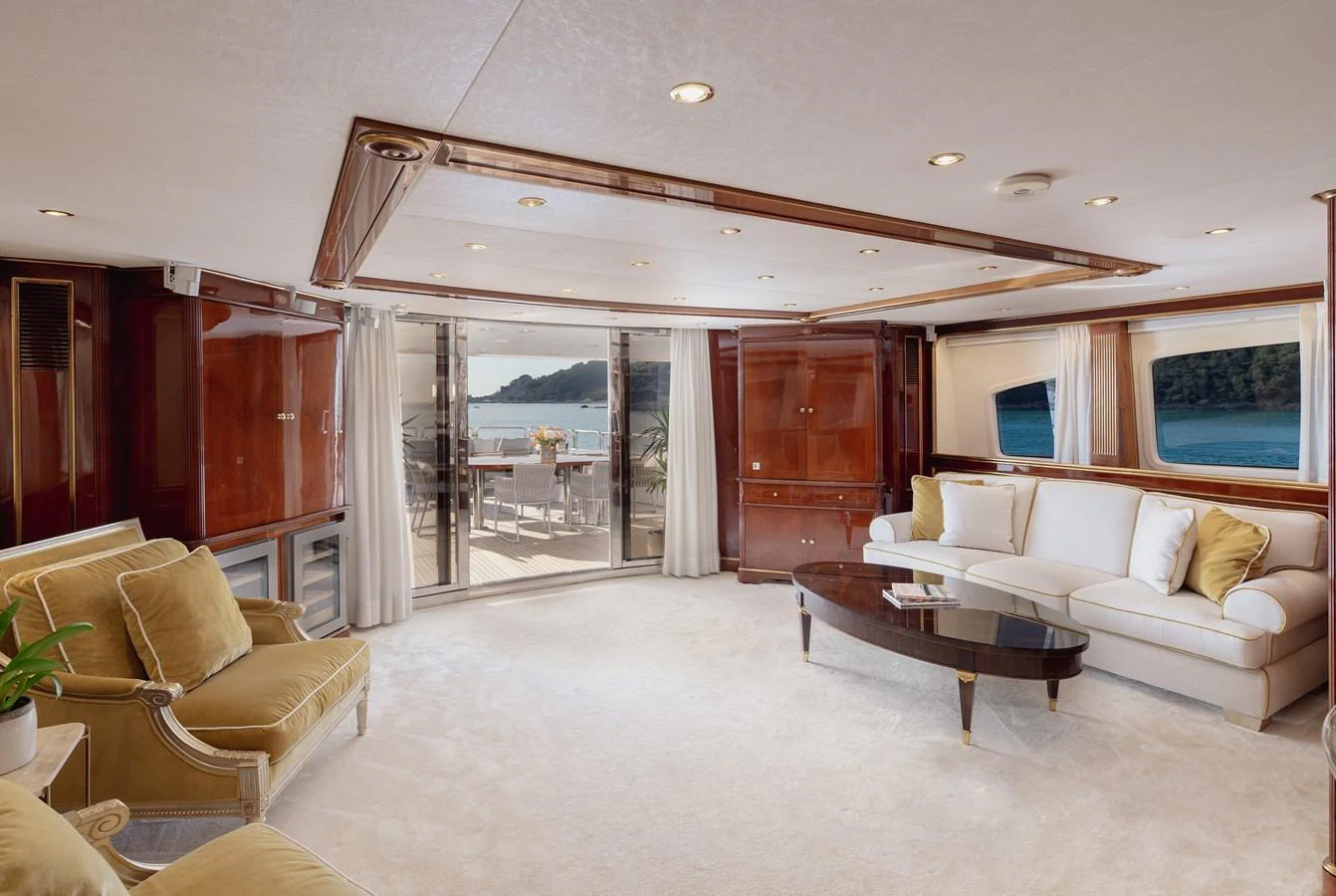The yacht's salon features elegant seating, rich wood accents, and large windows offering stunning views. aboard HOSHI Yacht for Sale