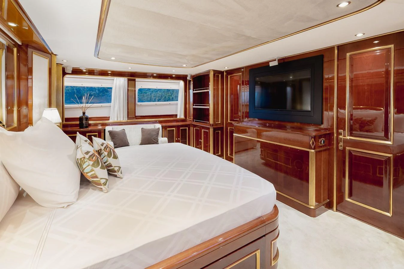 The master stateroom features luxurious wood paneling, a large bed, and a flat-screen TV. aboard HOSHI Yacht for Sale