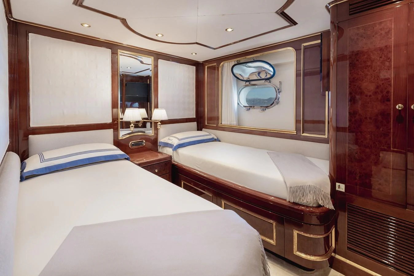 The guest stateroom features twin beds with elegant wood finishes and a porthole view. aboard HOSHI Yacht for Sale