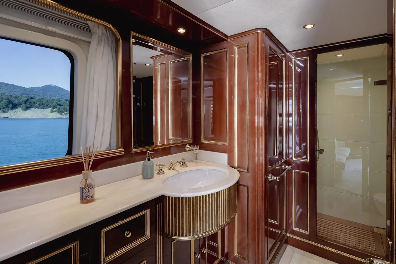 This luxurious yacht bathroom features elegant wood paneling and a large window with a scenic view. aboard HOSHI Yacht for Sale