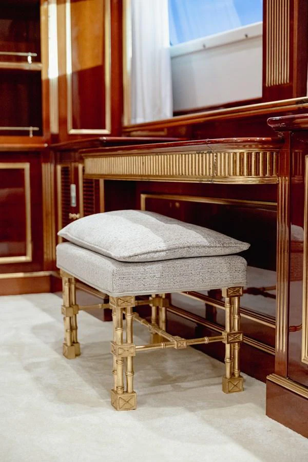 The image showcases an elegant interior space with a luxurious vanity and upholstered stool. aboard HOSHI Yacht for Sale