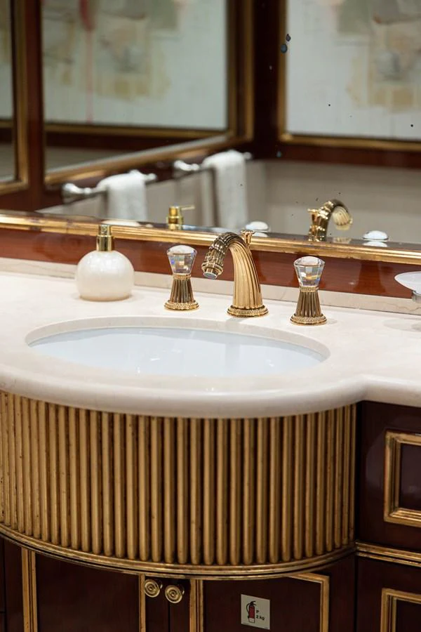 The bathroom features an elegant sink with gold accents and luxurious fixtures. aboard HOSHI Yacht for Sale