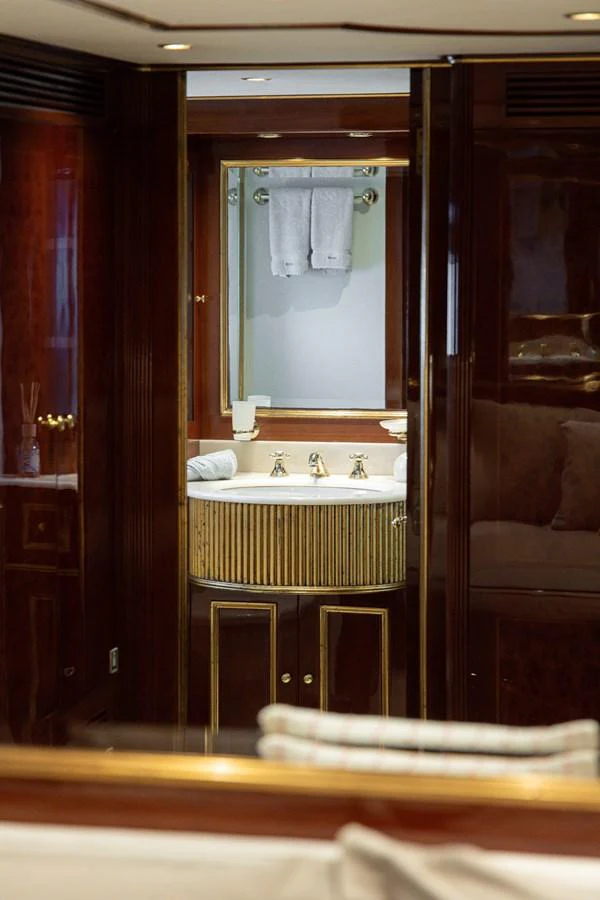 The yacht's bathroom features elegant wood paneling and a well-appointed sink area. aboard HOSHI Yacht for Sale