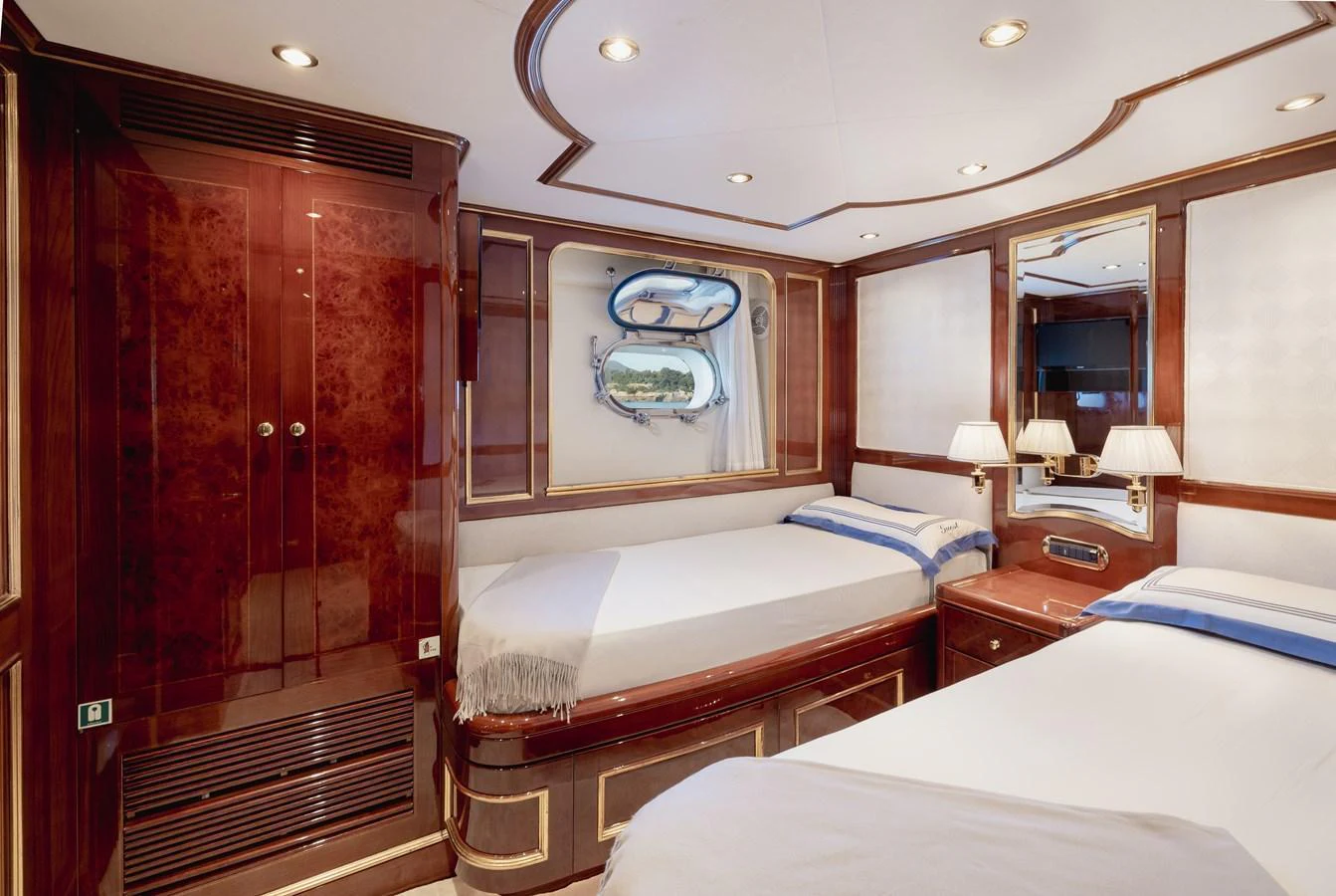 The guest stateroom features twin beds, elegant wood paneling, and a porthole window for natural light. aboard HOSHI Yacht for Sale