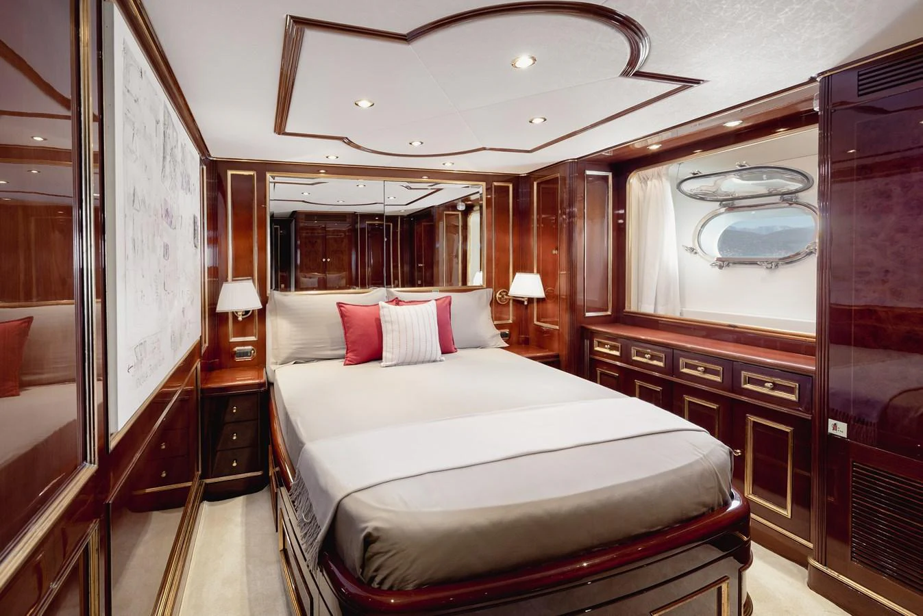 This luxurious stateroom features elegant wood paneling and a plush bed with accent pillows. aboard HOSHI Yacht for Sale