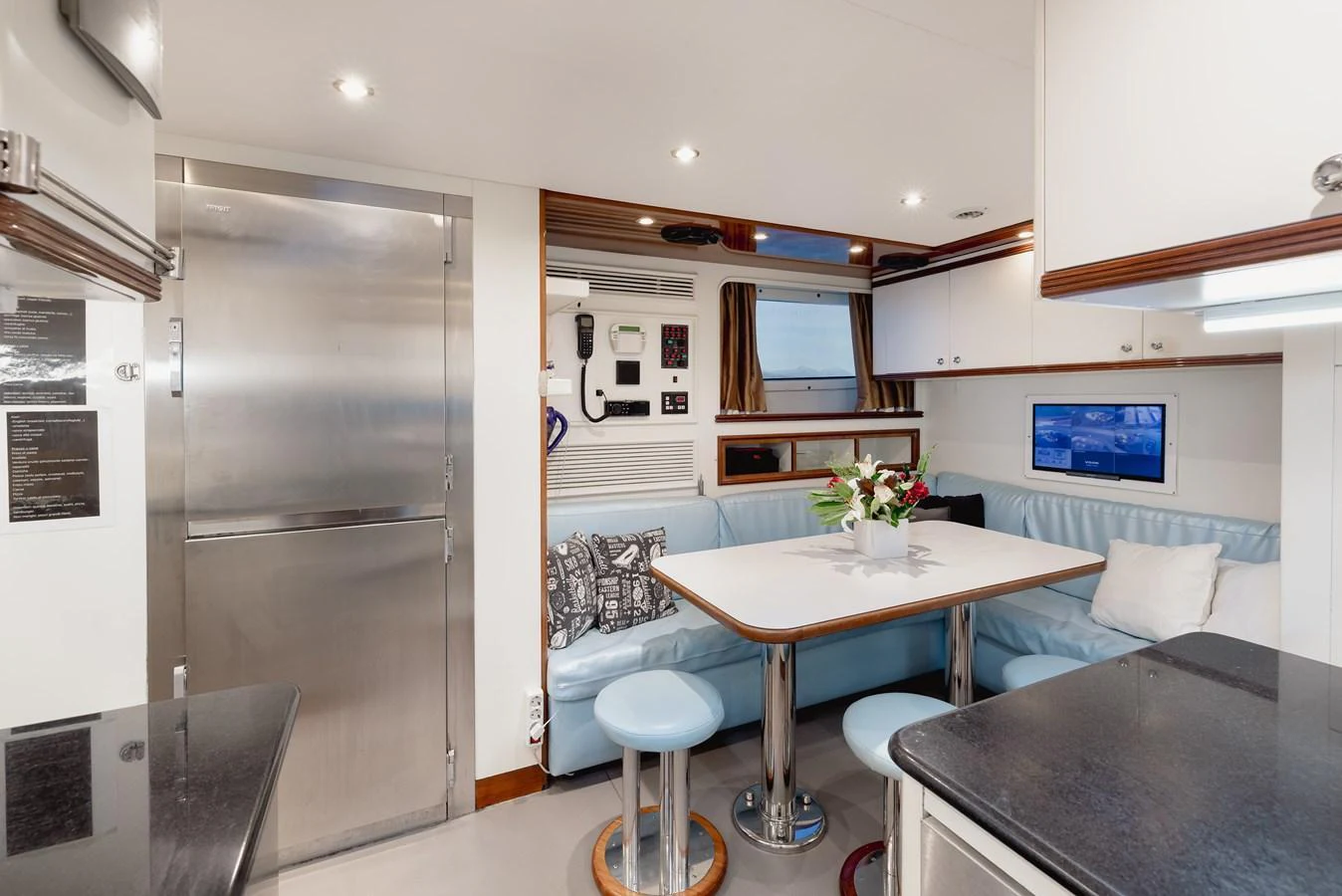 The yacht's galley features a cozy dining area with a light blue cushioned bench and a sleek table. aboard HOSHI Yacht for Sale