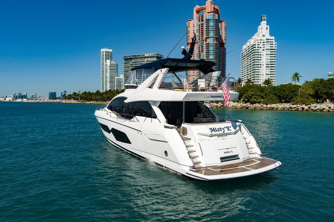 A sleek and modern yacht cruising in a vibrant coastal city setting. aboard MISTY K Yacht for Sale