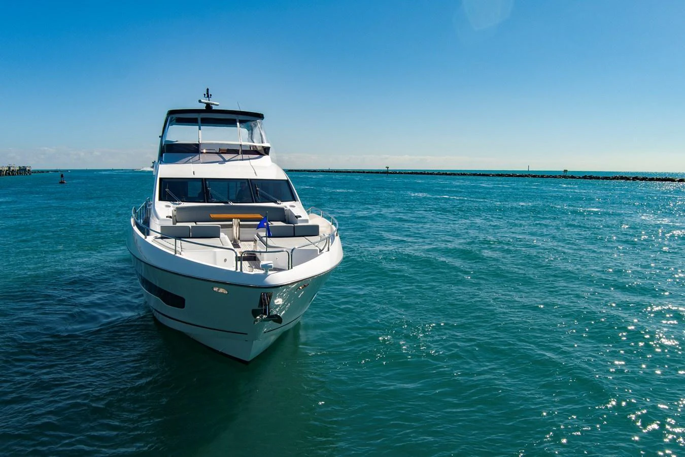 A sleek yacht glides through clear blue waters under a bright sky. aboard MISTY K Yacht for Sale