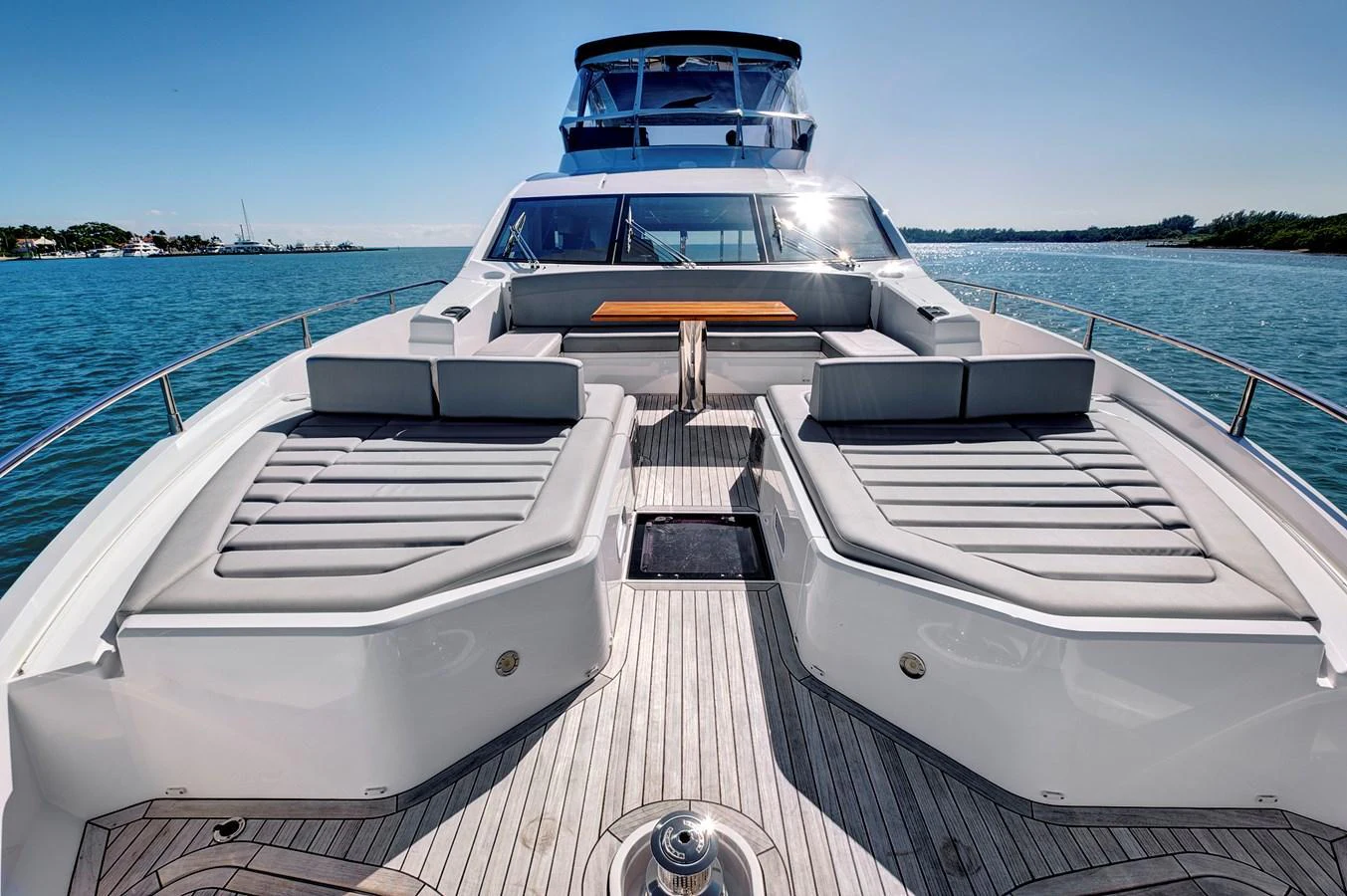 The foredeck features spacious sunbeds and a stylish seating area with a wooden table. aboard MISTY K Yacht for Sale